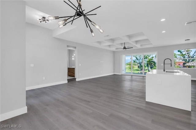 unfurnished living room with coffered ceiling, ceiling fan with notable chandelier, dark wood-type flooring, sink, and beam ceiling