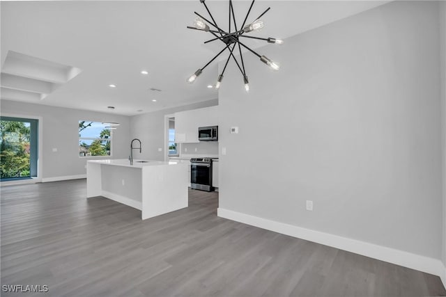 kitchen featuring sink, an island with sink, appliances with stainless steel finishes, white cabinetry, and a chandelier