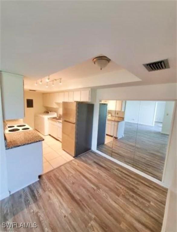 kitchen featuring white cabinets, washing machine and dryer, light hardwood / wood-style floors, and fridge