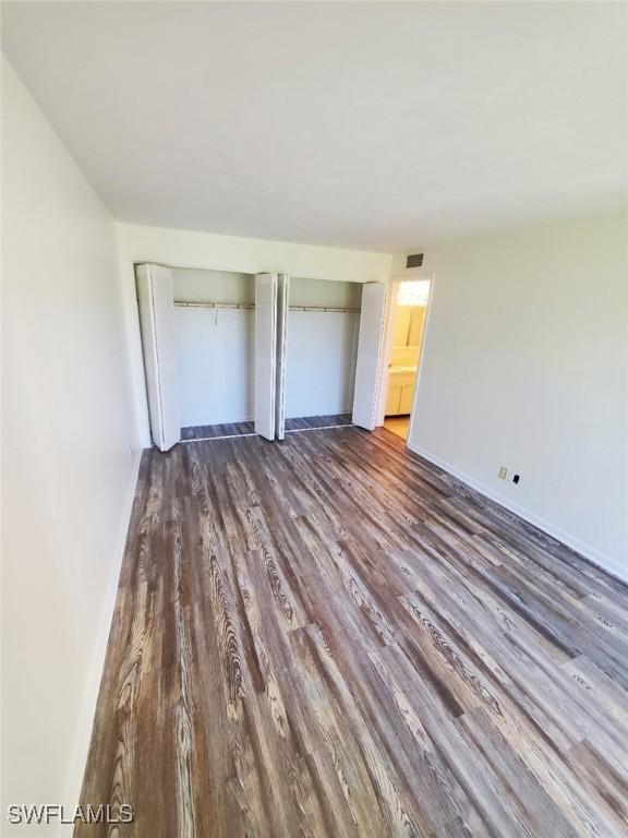 unfurnished bedroom featuring dark wood-type flooring and a closet