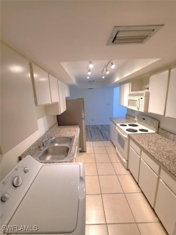 kitchen featuring washer / dryer, light tile patterned flooring, sink, white appliances, and white cabinets