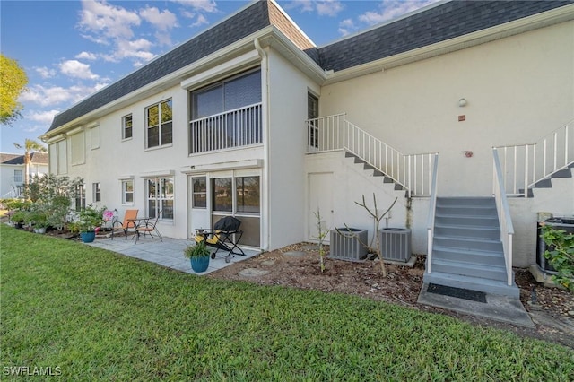 rear view of house with a patio area, central AC, and a lawn