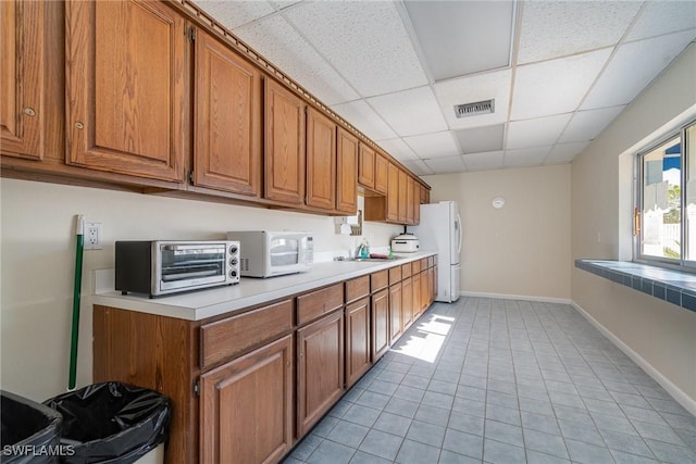 kitchen with a paneled ceiling, light tile patterned floors, sink, and white appliances