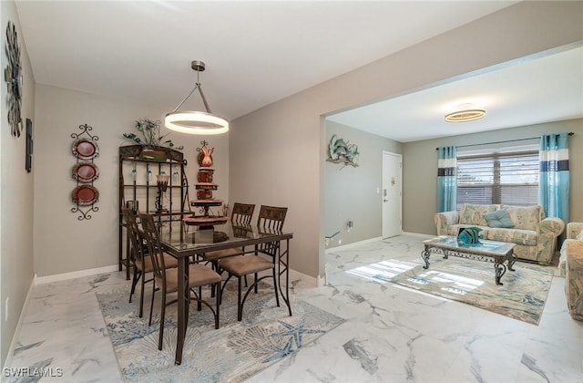 dining room featuring light marble finish flooring and baseboards