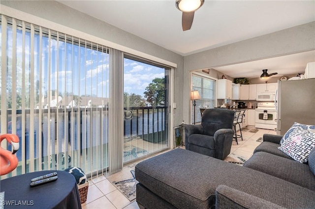 living room featuring light tile patterned flooring, ceiling fan, and a water view
