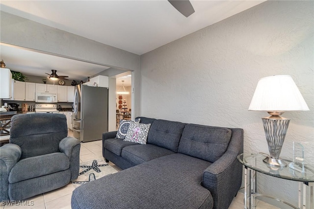 living area featuring a ceiling fan, light tile patterned flooring, and a textured wall