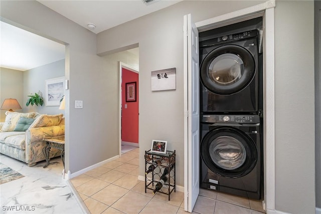 laundry room featuring light tile patterned floors and stacked washer and clothes dryer