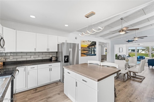 kitchen featuring decorative backsplash, stainless steel fridge, white cabinets, and black electric range