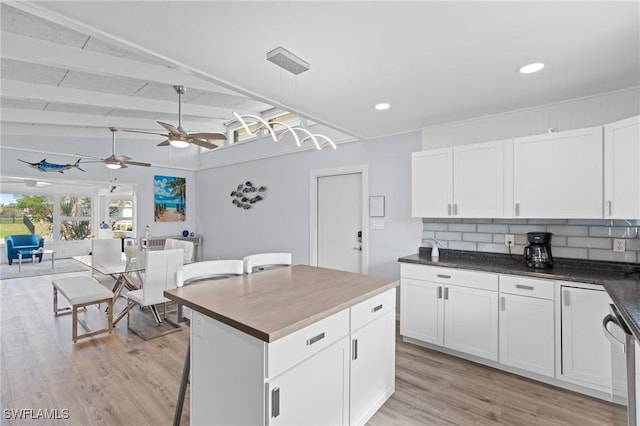 kitchen featuring white cabinetry, hanging light fixtures, lofted ceiling with beams, backsplash, and a kitchen island