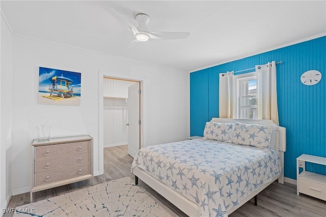 bedroom with wood-type flooring, a spacious closet, and ceiling fan