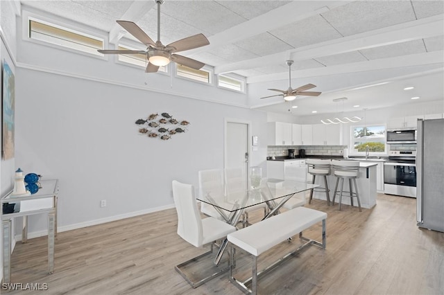 dining room with beam ceiling, ceiling fan, and light hardwood / wood-style flooring