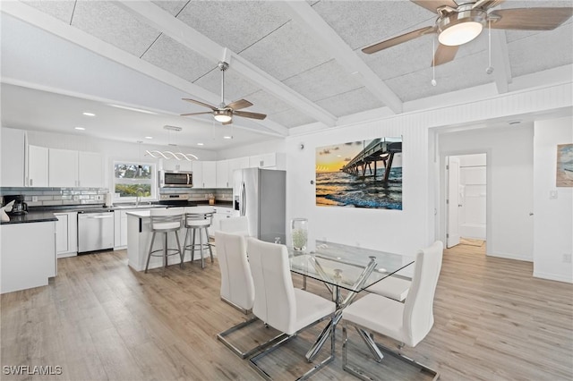 dining room with vaulted ceiling with beams, ceiling fan, and light wood-type flooring