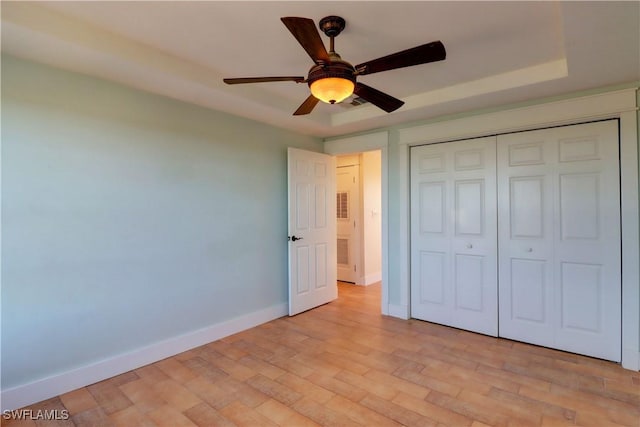 unfurnished bedroom with a closet, a raised ceiling, and ceiling fan