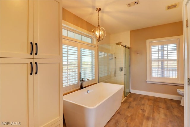 bathroom with toilet, hardwood / wood-style floors, separate shower and tub, and a notable chandelier