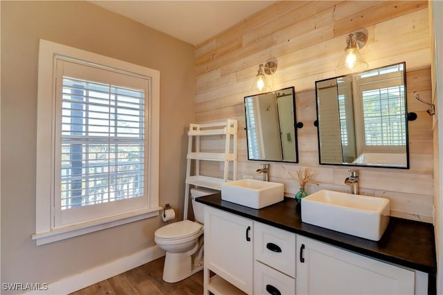 bathroom with decorative backsplash, vanity, wooden walls, wood-type flooring, and toilet