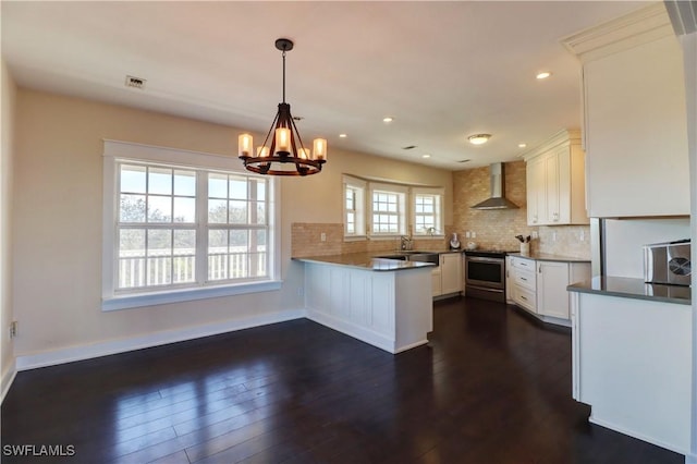 kitchen featuring white cabinetry, wall chimney exhaust hood, kitchen peninsula, decorative light fixtures, and stainless steel range with electric cooktop