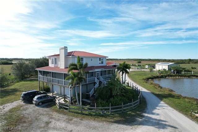 view of home's exterior with a water view, a garage, and a sunroom