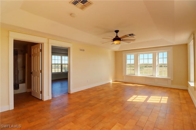 spare room with a tray ceiling, ceiling fan, and light hardwood / wood-style flooring