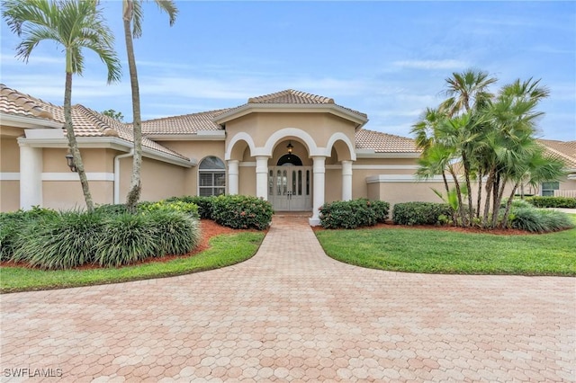 mediterranean / spanish-style home featuring a front yard and french doors