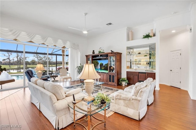 living room featuring light hardwood / wood-style flooring, ceiling fan, and crown molding