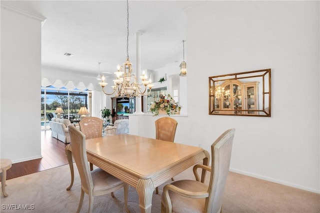 carpeted dining room with an inviting chandelier and ornamental molding