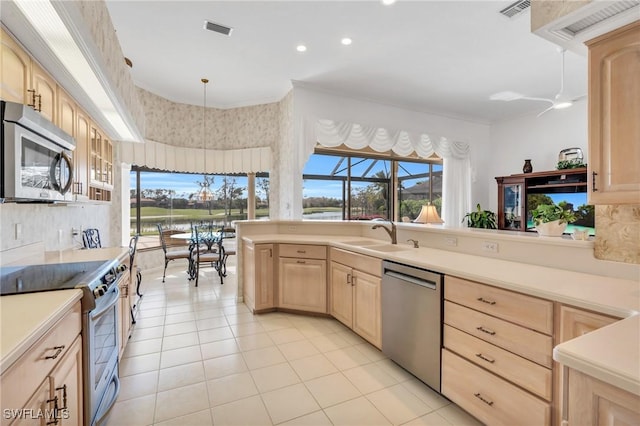 kitchen with ceiling fan, sink, hanging light fixtures, stainless steel appliances, and light brown cabinetry