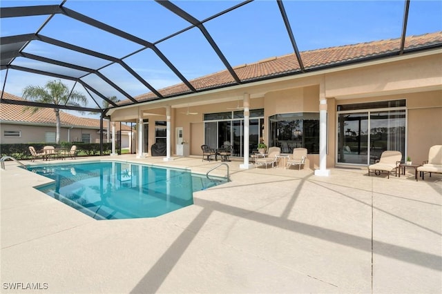 view of pool featuring glass enclosure, ceiling fan, and a patio