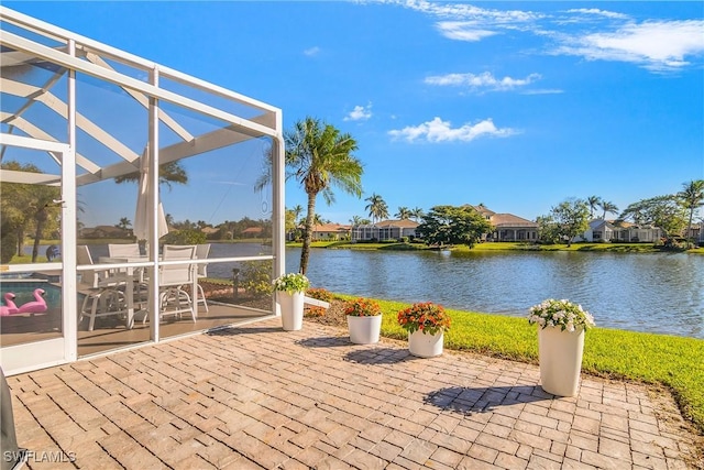 view of patio featuring glass enclosure and a water view