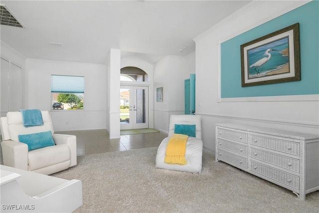 sitting room with light tile patterned floors, crown molding, and french doors