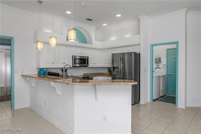 kitchen with kitchen peninsula, white cabinetry, washer and dryer, and stainless steel appliances