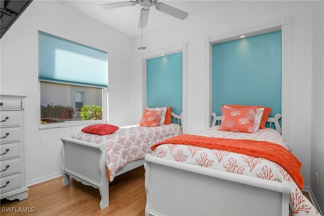 bedroom featuring ceiling fan, light hardwood / wood-style floors, and multiple windows