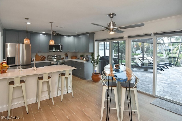 kitchen with appliances with stainless steel finishes, ceiling fan, a healthy amount of sunlight, pendant lighting, and a breakfast bar area