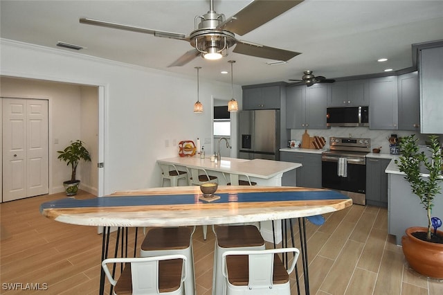 kitchen featuring gray cabinetry, sink, backsplash, appliances with stainless steel finishes, and ornamental molding