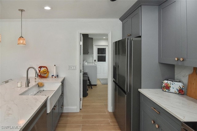 kitchen with pendant lighting, gray cabinets, light stone counters, washer / dryer, and stainless steel refrigerator