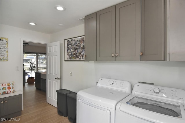 washroom featuring light hardwood / wood-style floors, cabinets, and washing machine and clothes dryer