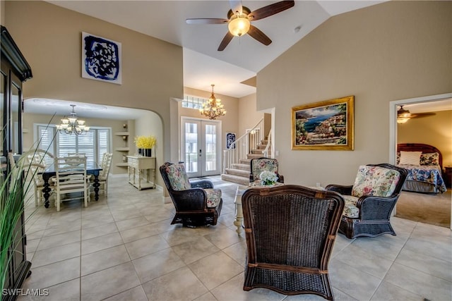 tiled living room with ceiling fan with notable chandelier, high vaulted ceiling, and french doors