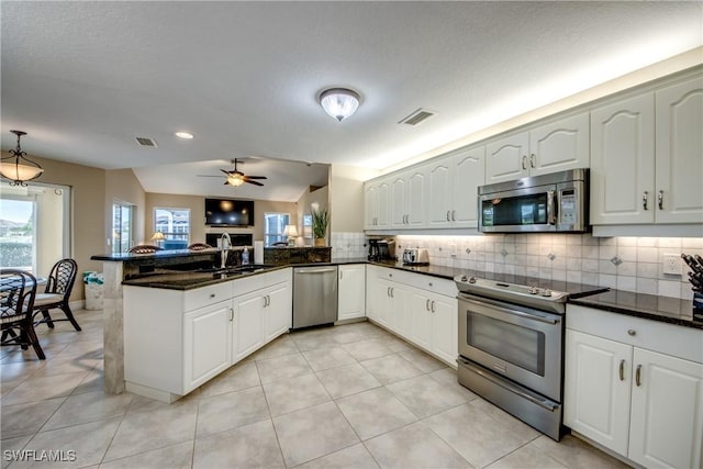 kitchen with kitchen peninsula, sink, light tile patterned floors, appliances with stainless steel finishes, and white cabinetry