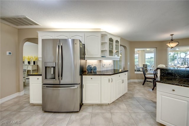 kitchen with dark stone countertops, light tile patterned floors, white cabinets, and stainless steel refrigerator with ice dispenser