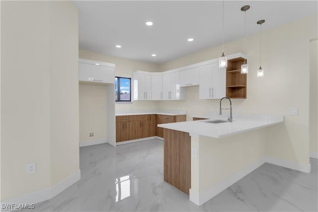 kitchen with white cabinets, decorative light fixtures, kitchen peninsula, and sink