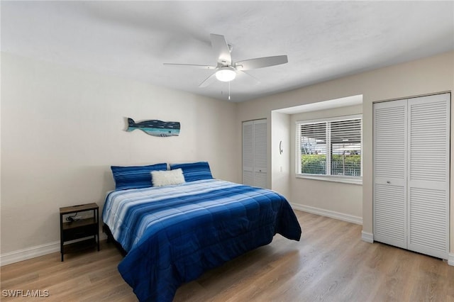 bedroom featuring two closets, ceiling fan, and hardwood / wood-style floors