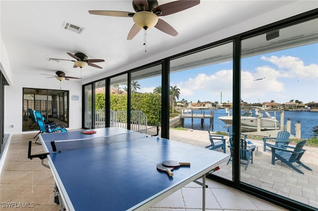 recreation room featuring ceiling fan, light tile patterned floors, and a water view