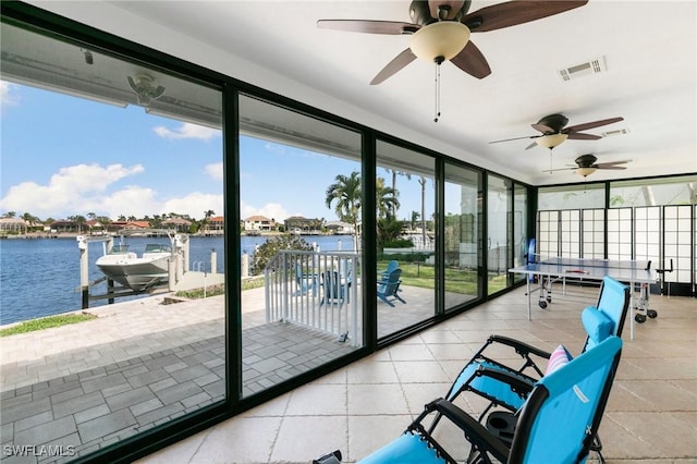 sunroom featuring ceiling fan and a water view