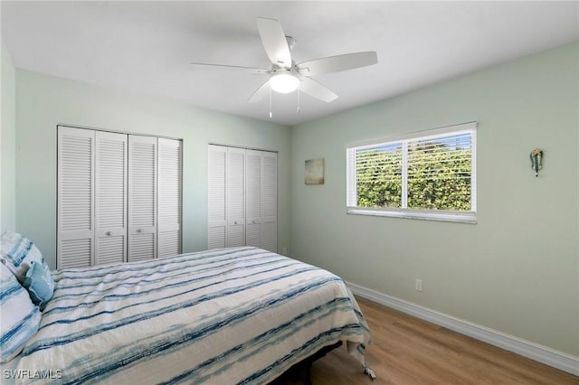 bedroom featuring two closets, ceiling fan, and hardwood / wood-style flooring