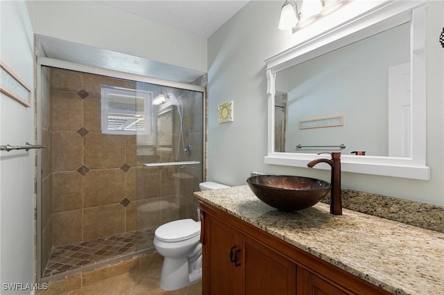 bathroom featuring toilet, a shower with door, tile patterned floors, and vanity