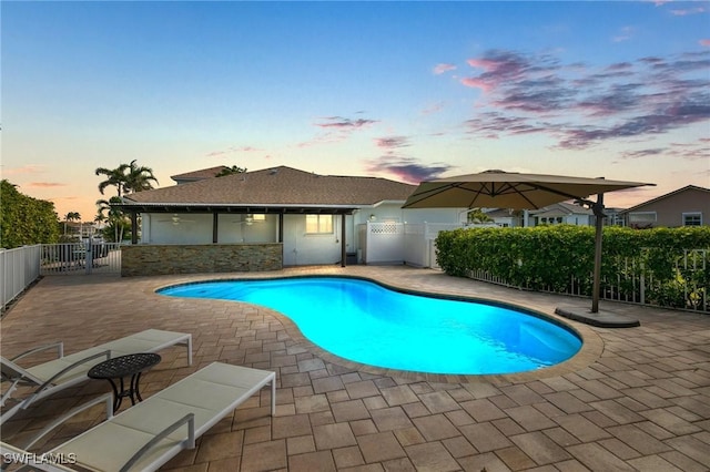 pool at dusk featuring a patio area