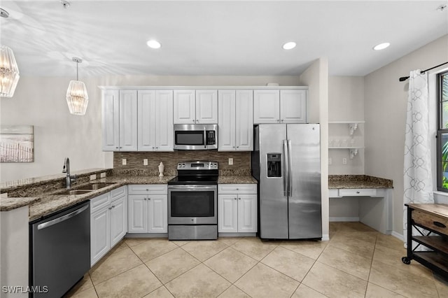 kitchen featuring sink, stainless steel appliances, dark stone countertops, decorative light fixtures, and white cabinets