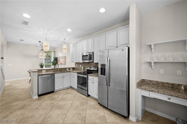 kitchen with sink, kitchen peninsula, decorative light fixtures, white cabinets, and appliances with stainless steel finishes