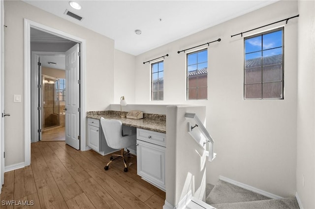 home office featuring built in desk and light hardwood / wood-style flooring