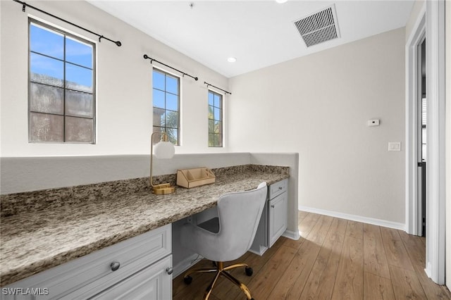 office space with a healthy amount of sunlight, built in desk, and light hardwood / wood-style floors