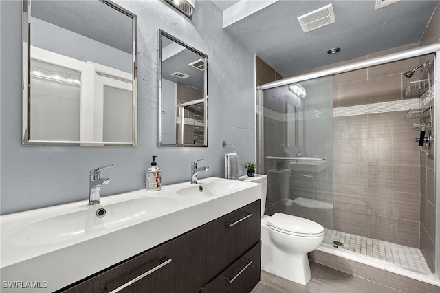 bathroom with a shower with door, vanity, and toilet